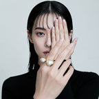 Close-up of a hand wearing a gold open ring with two irregular white pearls
