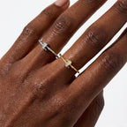 Close-up of a hand wearing two twisted rope adjustable rings in silver and gold tones, each set with zircon stones, stacked minimalist rings by OMŌN Jewelry.