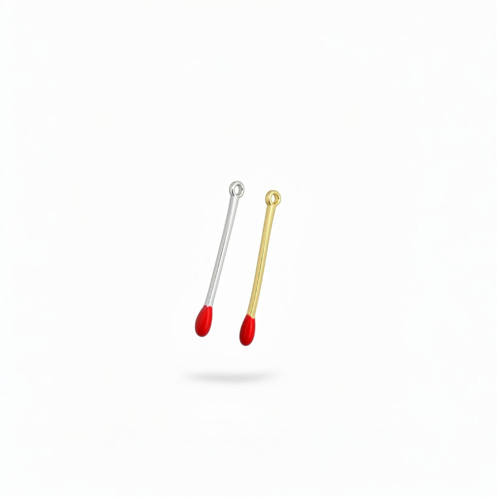 Gold and silver matchstick enamel charm pendants with red tips floating on white background