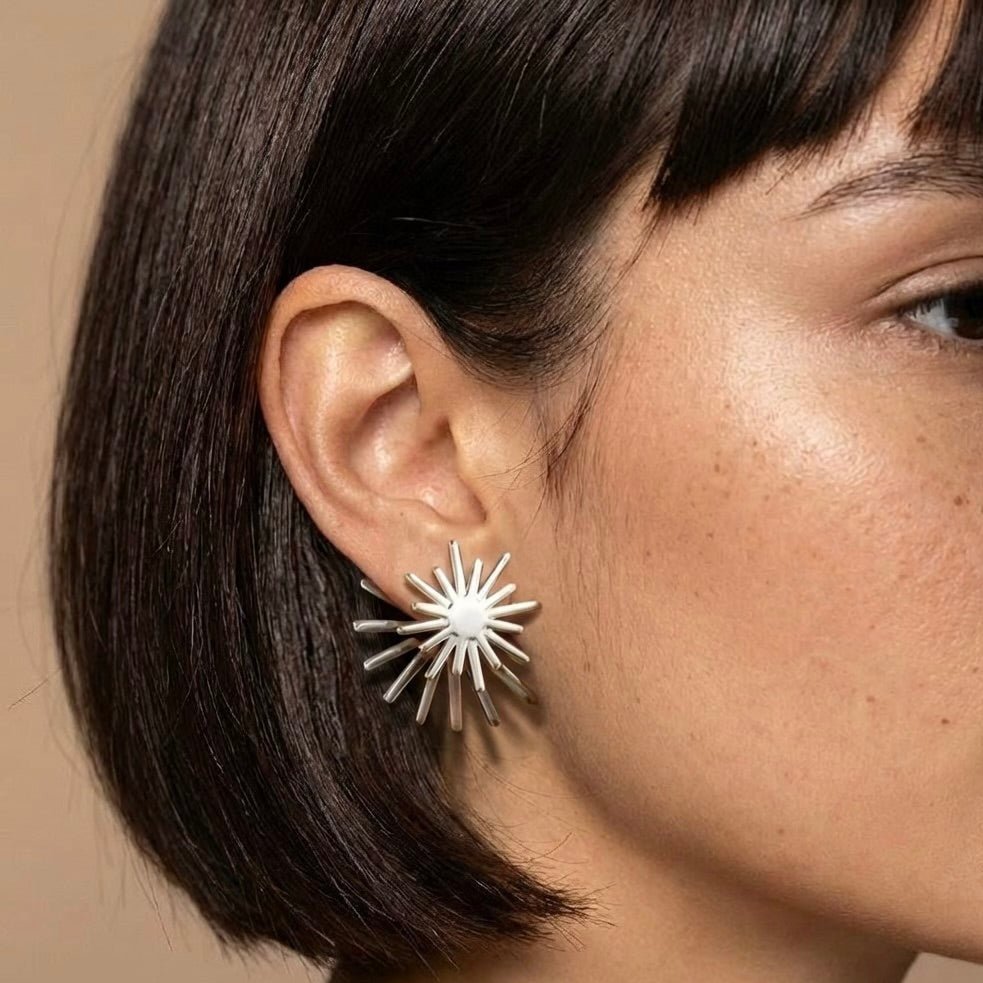 Model wearing spinning sunburst earrings – silver tone